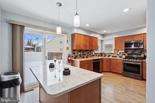 kitchen with sink, light hardwood / wood-style flooring, stainless steel appliances, decorative backsplash, and decorative light fixtures