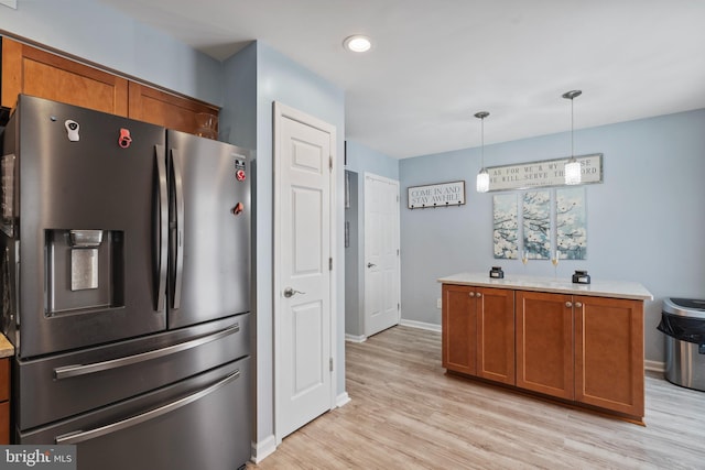 kitchen featuring stainless steel fridge with ice dispenser, decorative light fixtures, and light hardwood / wood-style floors