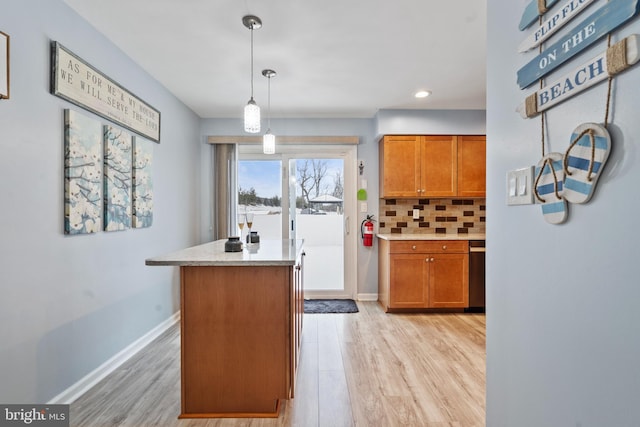 kitchen with hanging light fixtures, decorative backsplash, light hardwood / wood-style floors, and a kitchen island