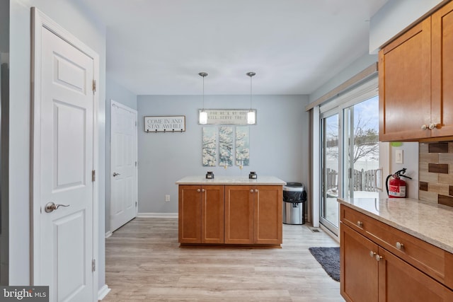 kitchen with tasteful backsplash, hanging light fixtures, and light hardwood / wood-style floors