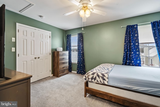 bedroom featuring multiple windows, light colored carpet, a closet, and ceiling fan