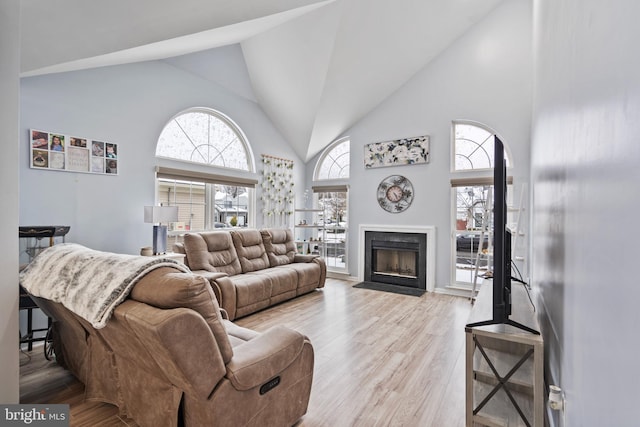 living room featuring high vaulted ceiling and light wood-type flooring