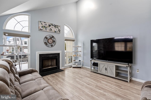 living room featuring high vaulted ceiling and light hardwood / wood-style floors