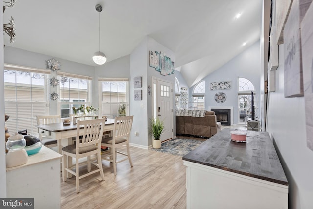 dining room featuring high vaulted ceiling and light wood-type flooring