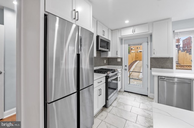 kitchen featuring white cabinetry, light stone countertops, decorative backsplash, and stainless steel appliances