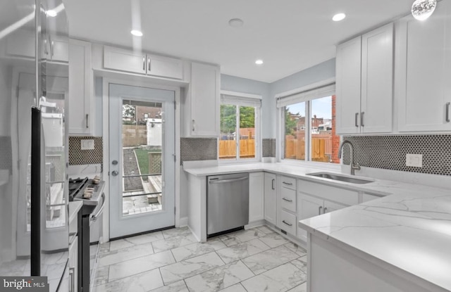 kitchen featuring white cabinetry, stainless steel appliances, light stone countertops, and sink