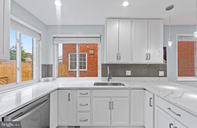 kitchen featuring sink, hanging light fixtures, dishwasher, light stone countertops, and white cabinets