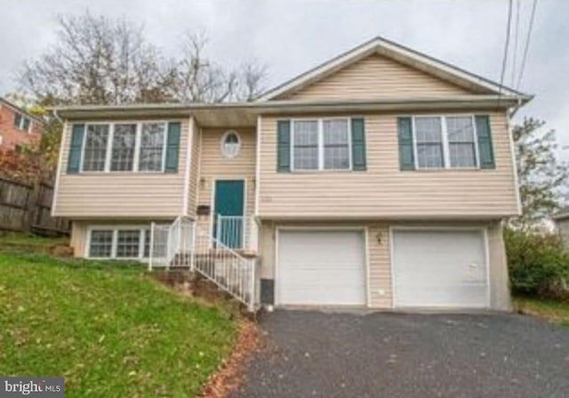 split foyer home featuring an attached garage, a front lawn, and aphalt driveway