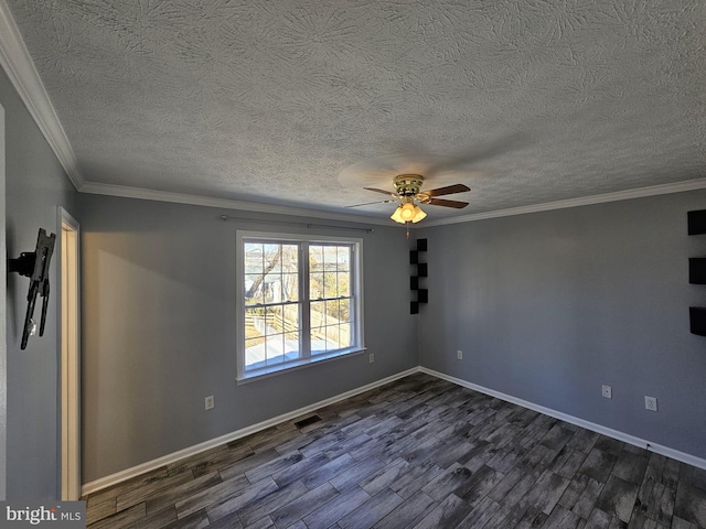 spare room featuring dark wood finished floors, visible vents, ornamental molding, a ceiling fan, and baseboards