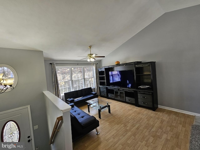 living room featuring vaulted ceiling, light wood finished floors, a ceiling fan, and baseboards