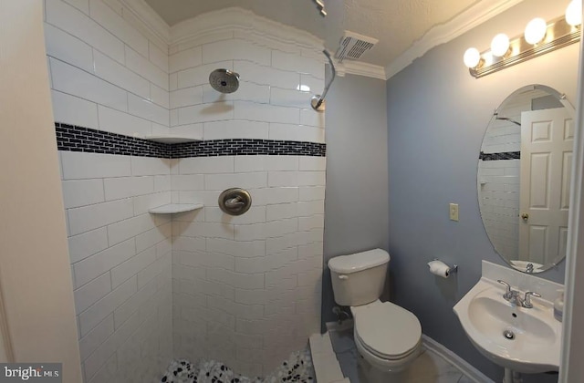 full bathroom with tiled shower, a sink, and visible vents