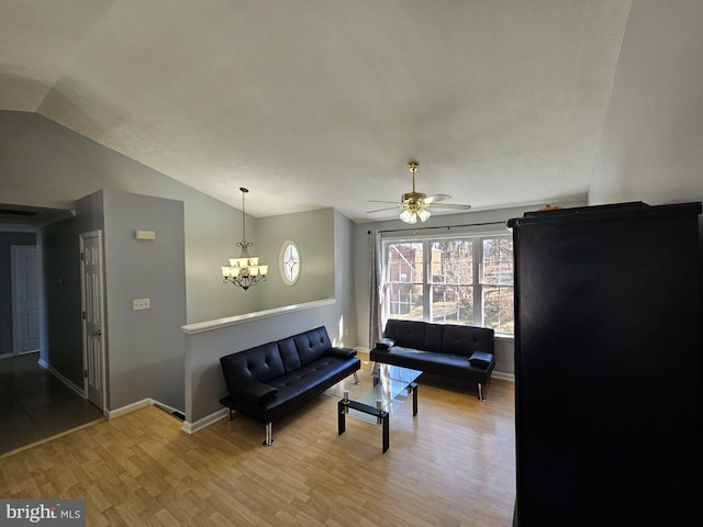 living room featuring lofted ceiling, baseboards, wood finished floors, and ceiling fan with notable chandelier