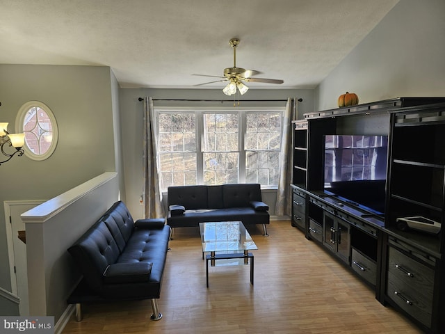 living area featuring light wood-style floors, a ceiling fan, and a textured ceiling