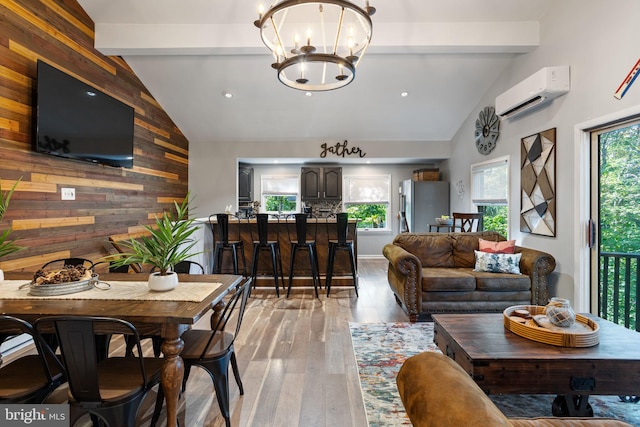 living room with a notable chandelier, a wealth of natural light, a wall mounted AC, and wood walls