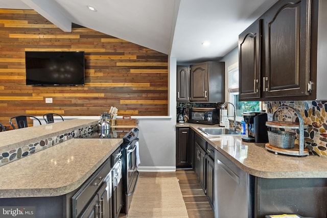 kitchen with sink, appliances with stainless steel finishes, vaulted ceiling with beams, dark hardwood / wood-style flooring, and wood walls