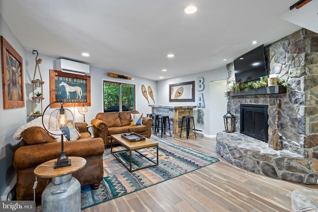 living room with hardwood / wood-style flooring, bar, a stone fireplace, and a wall mounted AC