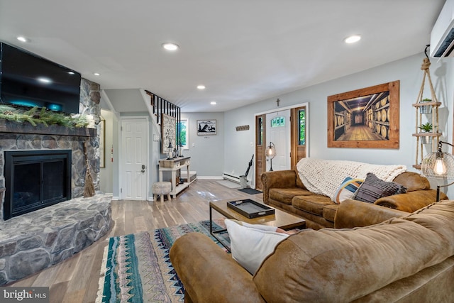 living room with hardwood / wood-style flooring, a baseboard radiator, a fireplace, and a wall mounted AC