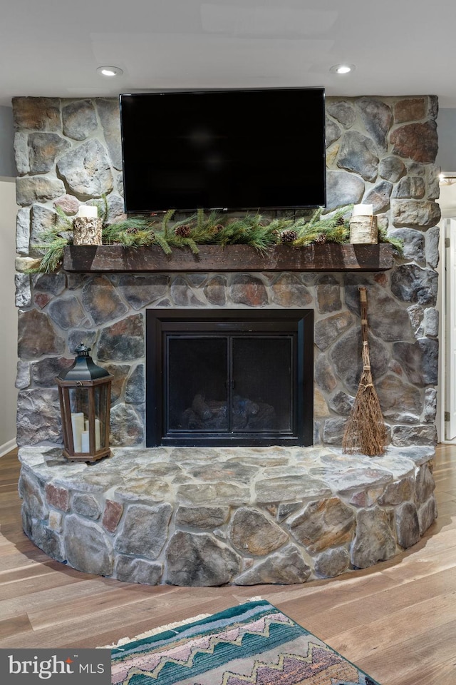 room details with hardwood / wood-style flooring and a stone fireplace