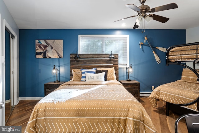 bedroom with a baseboard heating unit, dark wood-type flooring, and ceiling fan