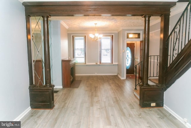 foyer featuring crown molding, decorative columns, an inviting chandelier, and light hardwood / wood-style flooring