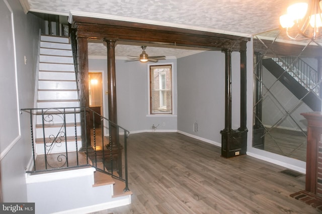 interior space featuring hardwood / wood-style floors, ceiling fan with notable chandelier, and ornamental molding