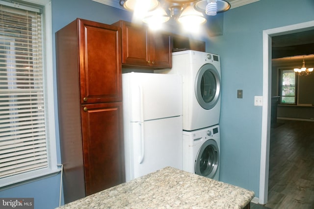 washroom with hardwood / wood-style flooring, cabinets, stacked washer / dryer, and a chandelier