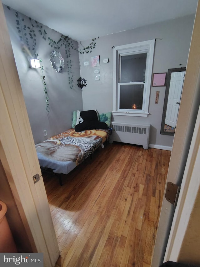 bedroom featuring hardwood / wood-style flooring and radiator heating unit