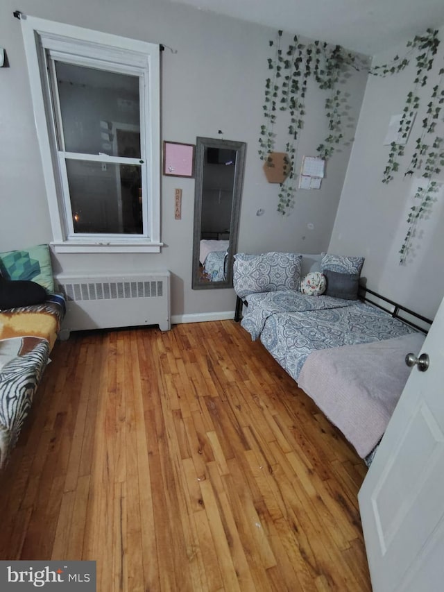 bedroom featuring radiator heating unit and light wood-type flooring