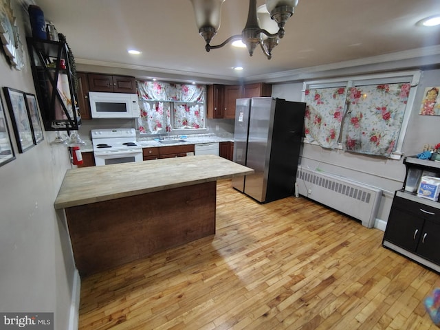 kitchen with radiator, white appliances, ornamental molding, and light wood-type flooring