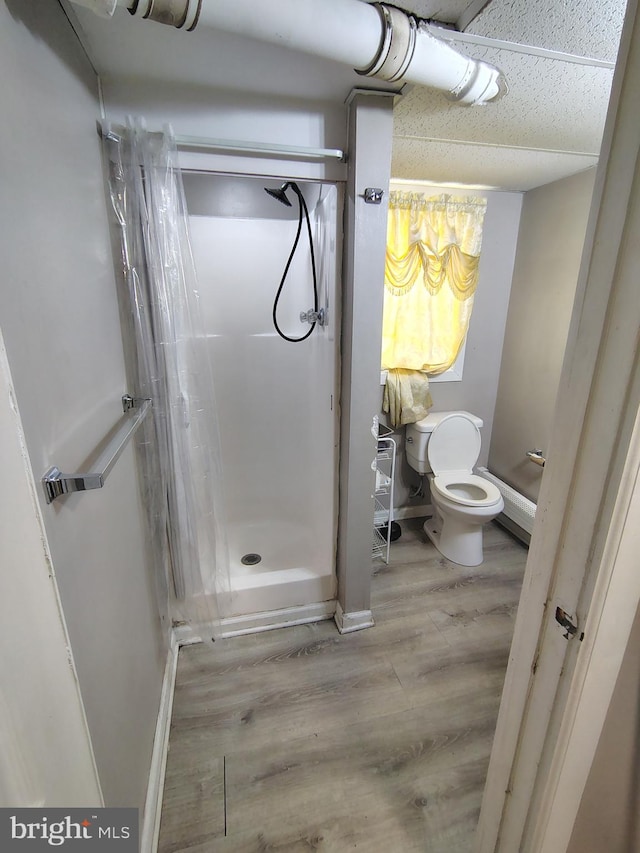 bathroom with wood-type flooring, toilet, and a shower with shower curtain