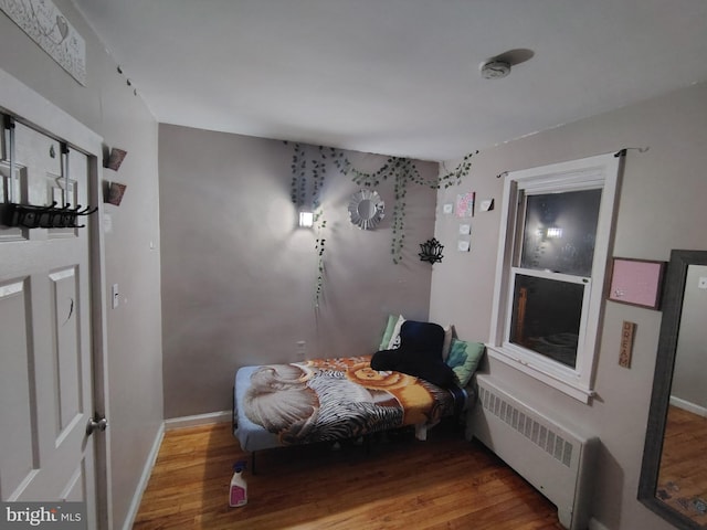 bedroom featuring hardwood / wood-style floors and radiator heating unit