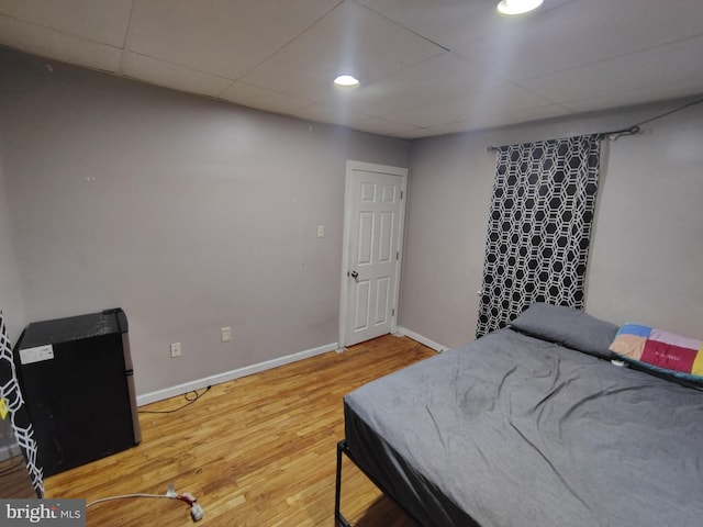 bedroom featuring hardwood / wood-style flooring and a drop ceiling