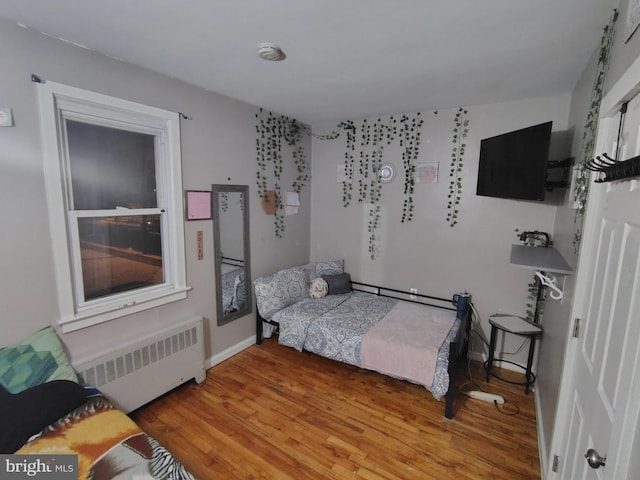 bedroom featuring hardwood / wood-style floors and radiator heating unit