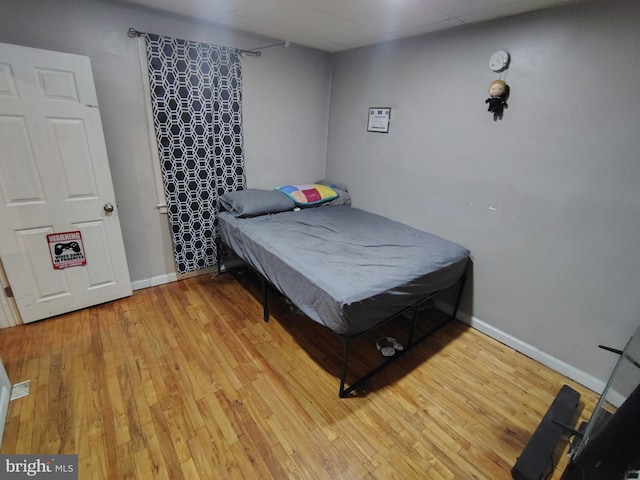 bedroom featuring a drop ceiling and light wood-type flooring