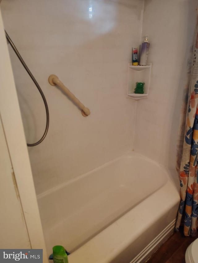 bathroom with toilet, hardwood / wood-style floors, and shower / bath combo