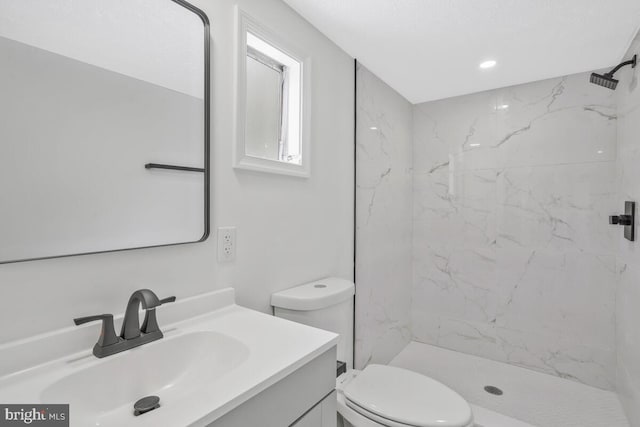 bathroom with vanity, toilet, and a tile shower