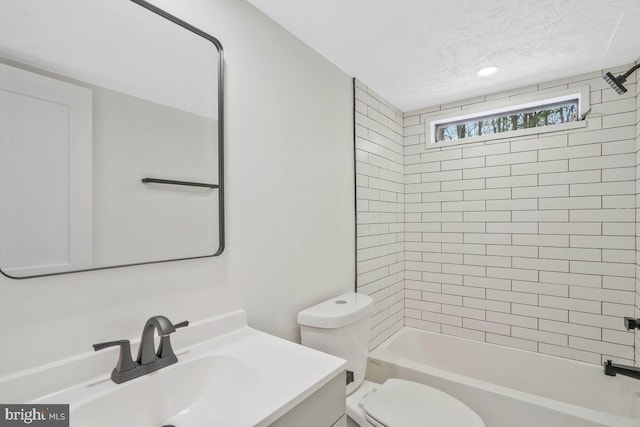 full bathroom featuring vanity, tiled shower / bath combo, toilet, and a textured ceiling