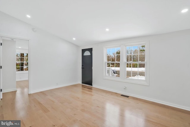 foyer entrance with vaulted ceiling and light hardwood / wood-style floors