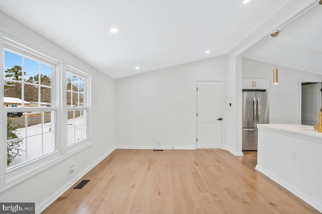 spare room featuring vaulted ceiling and light wood-type flooring