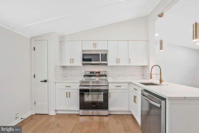 kitchen featuring appliances with stainless steel finishes, sink, white cabinets, and decorative light fixtures