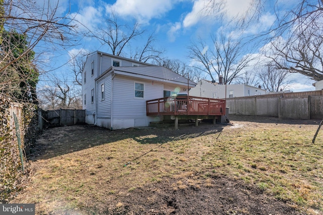 back of property with a deck and a lawn