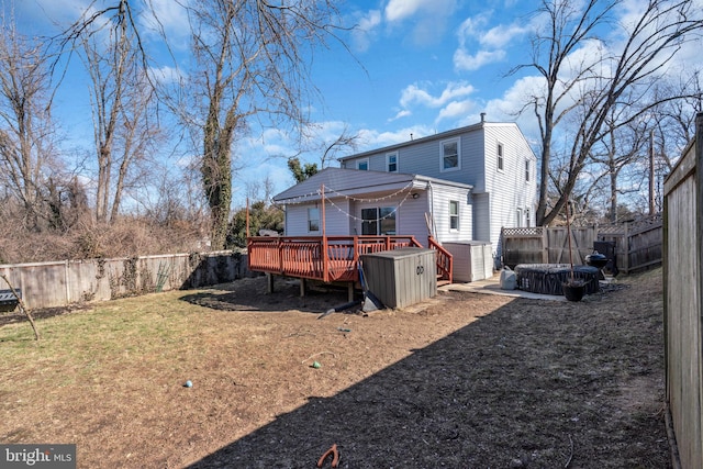 rear view of property featuring a yard, a shed, and a wooden deck