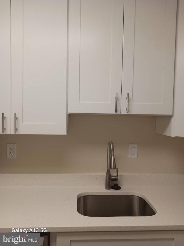 room details with light stone countertops, sink, and white cabinets