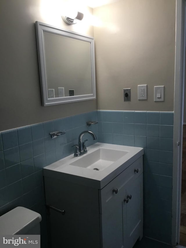 bathroom featuring vanity, tile walls, and toilet