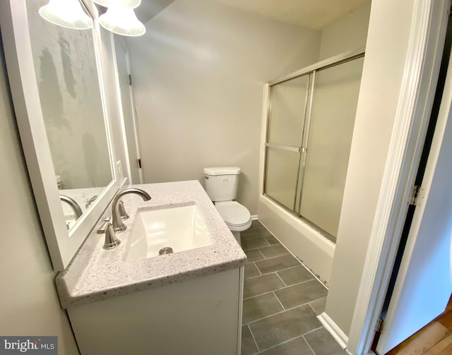 full bathroom with vanity, bath / shower combo with glass door, and toilet