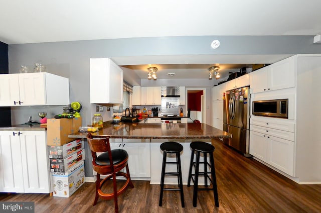 kitchen featuring appliances with stainless steel finishes, white cabinetry, a breakfast bar, and kitchen peninsula