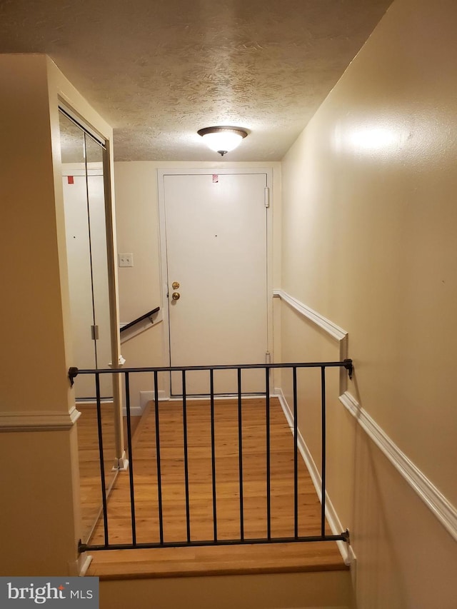 stairs featuring hardwood / wood-style flooring and a textured ceiling