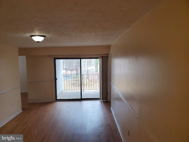 empty room with hardwood / wood-style flooring and a textured ceiling