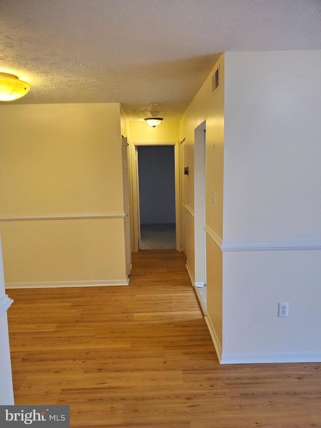 hall featuring a textured ceiling and light hardwood / wood-style floors