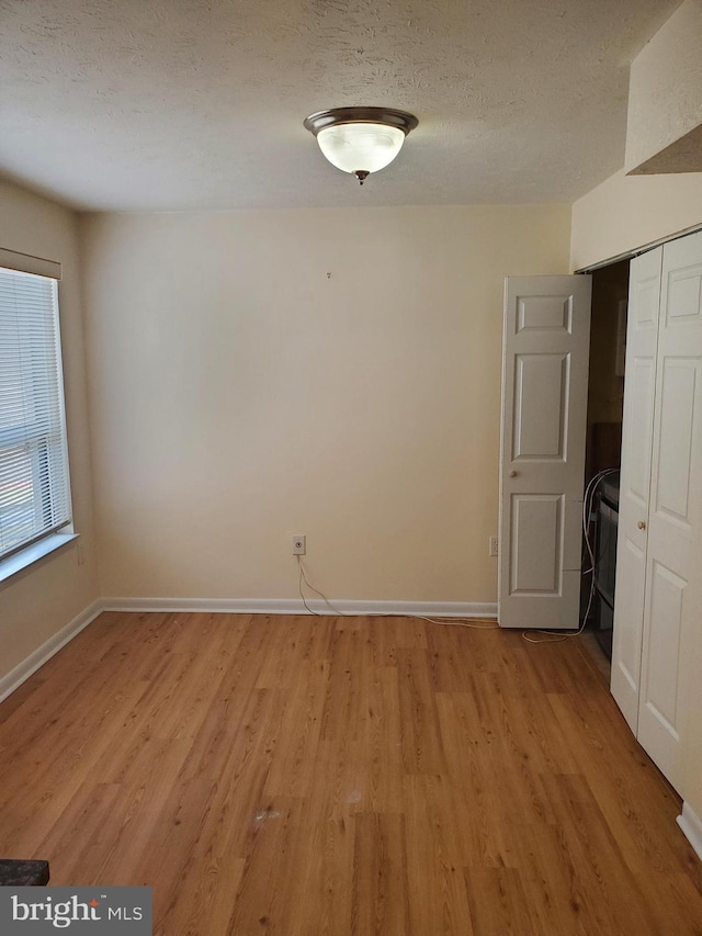 unfurnished room with a textured ceiling and light wood-type flooring